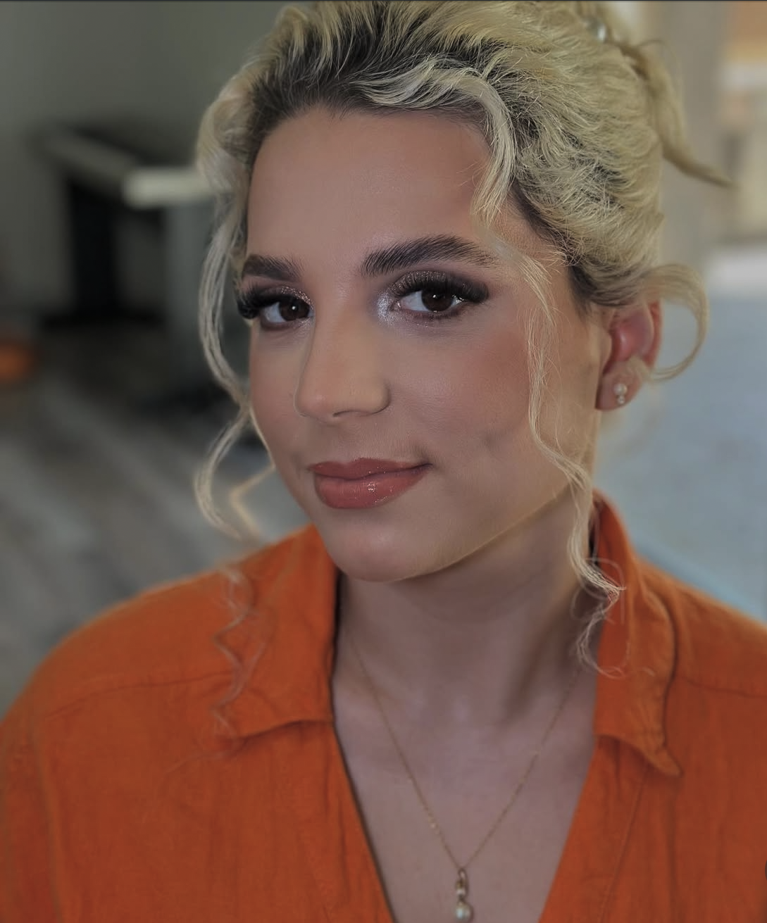 Blonde occasion updo with soft glam makeup and pearl details