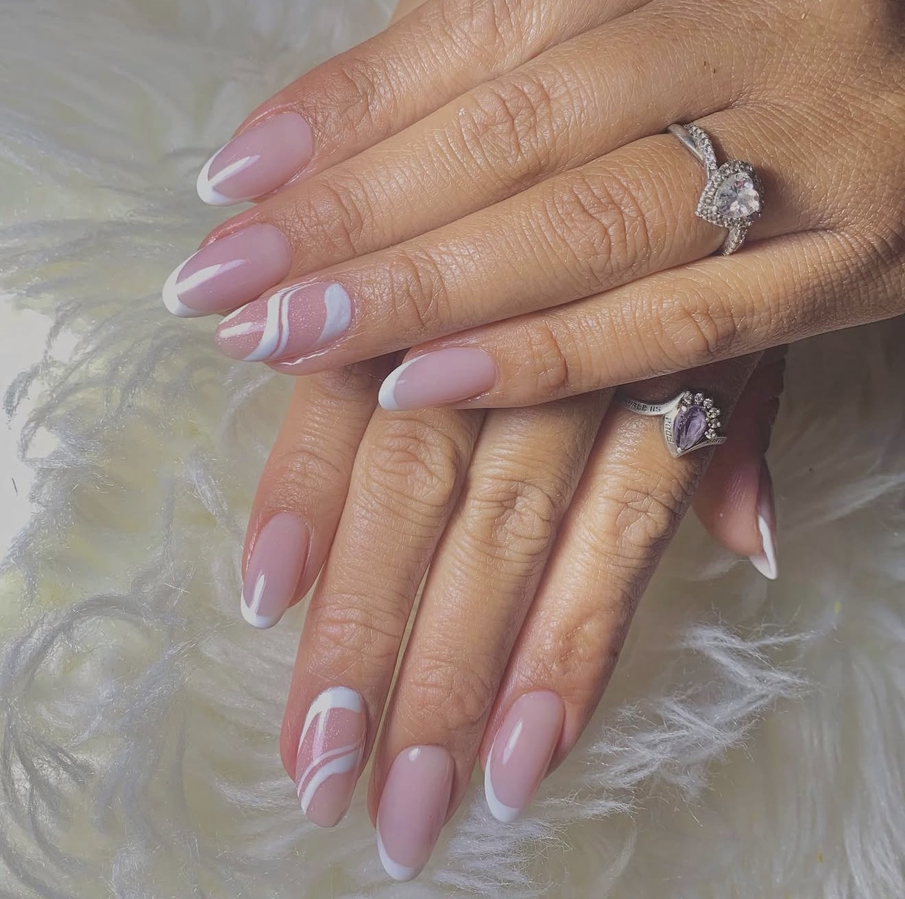 Nude almond nails with white French tips and swirl accents